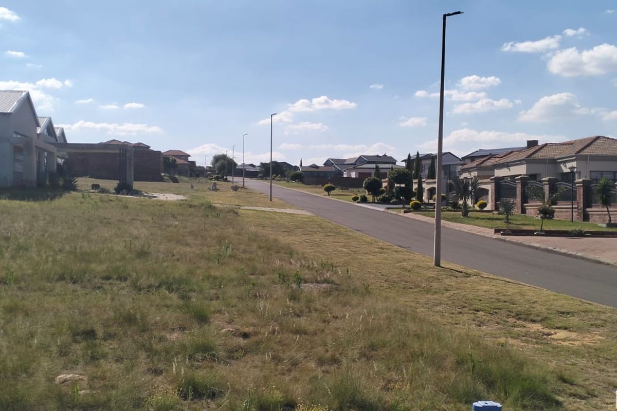 A view of a paved residential street in a suburban neighborhood with surrounding houses and street lighting.