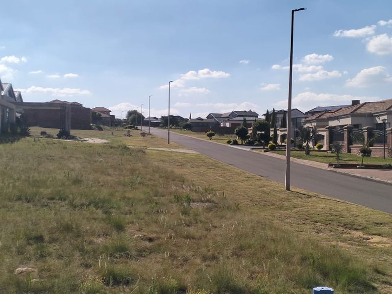 A view of a paved residential street in a suburban neighborhood with surrounding houses and street lighting.