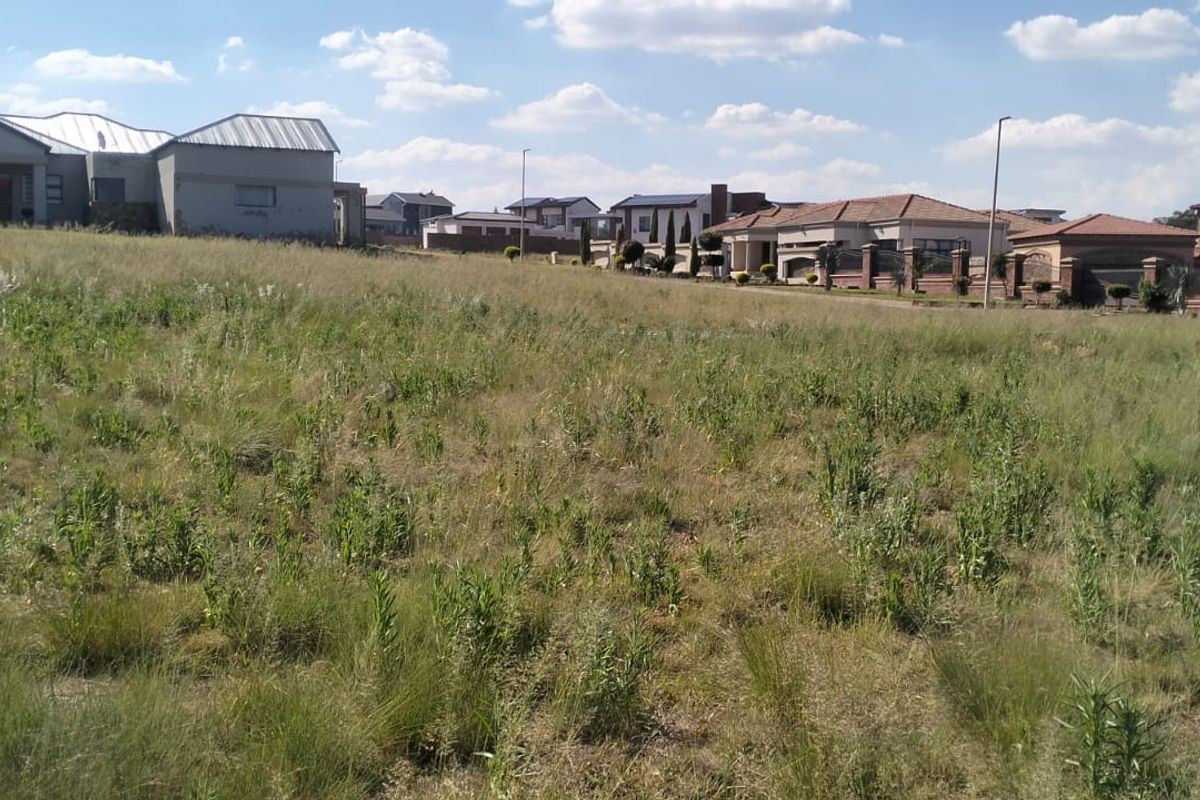 A view of a vacant residential plot of land situated in a developed neighborhood with surrounding houses.