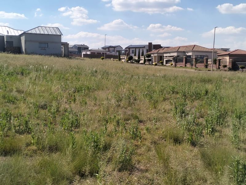 A view of a vacant residential plot of land situated in a developed neighborhood with surrounding houses.
