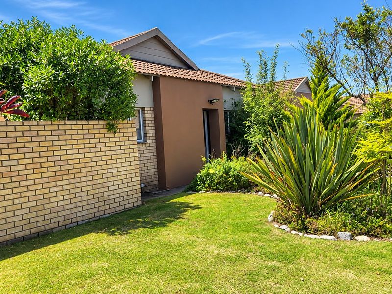 A well-maintained front exterior view of the house featuring a brick boundary wall, landscaped garden, and tiled roof architecture.