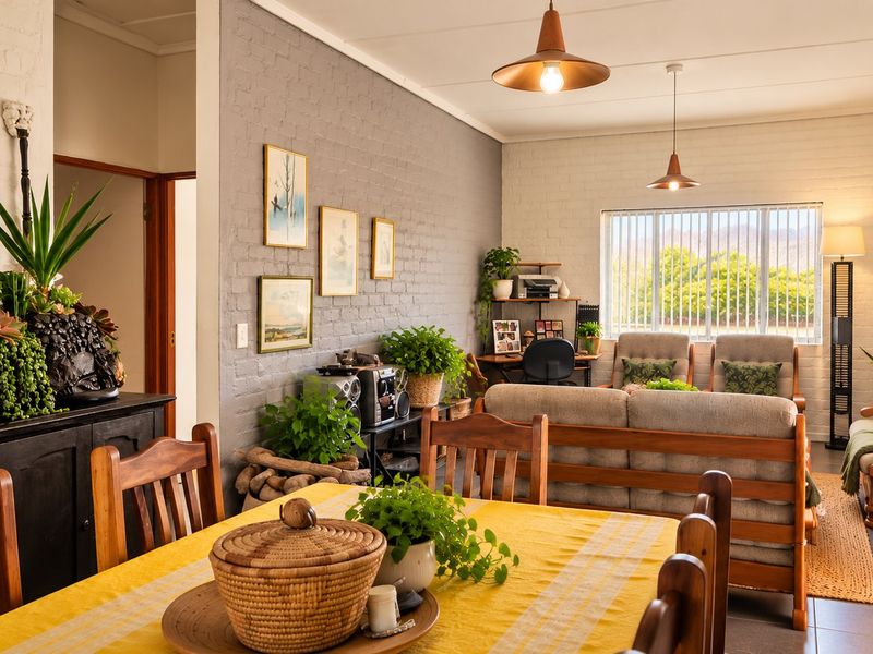 Spacious open-plan living and dining area featuring exposed brick walls, tiled flooring, and natural light through vertical blinds.