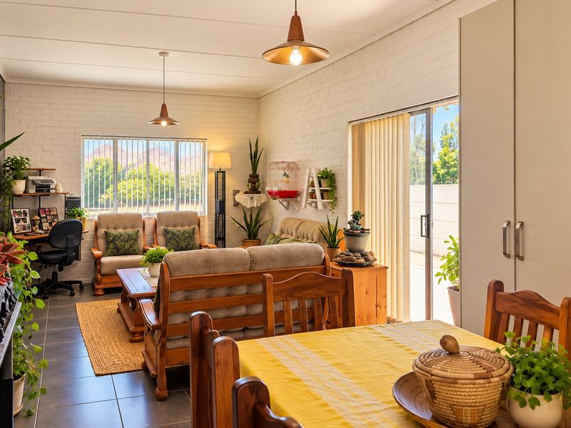 Bright open-plan living and dining area featuring tiled floors, painted brick walls, and a sliding door providing access to the outdoor space.