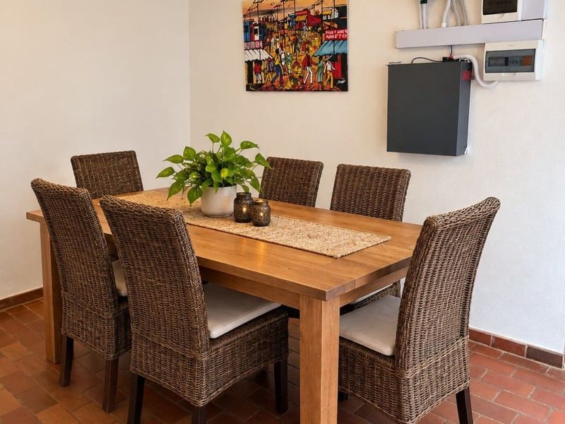 A dining area featuring terracotta tile flooring and wall-mounted solar power infrastructure, providing a functional space for meals.
