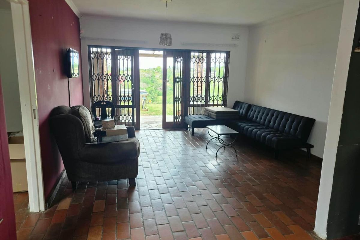 Spacious living room featuring terracotta tile flooring, security gates, and sliding glass doors providing direct access to the outdoor area.