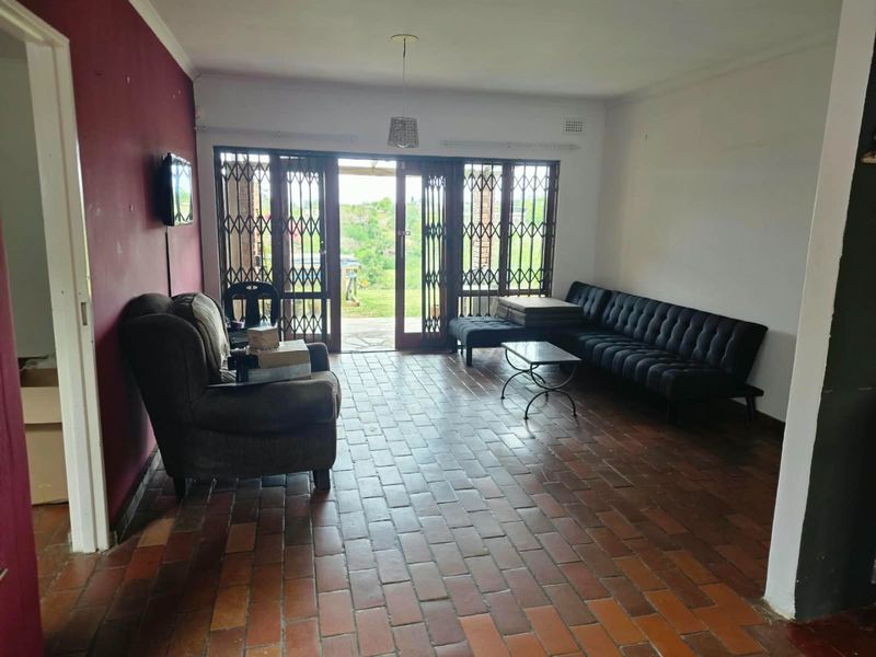 Spacious living room featuring terracotta tile flooring, security gates, and sliding glass doors providing direct access to the outdoor area.