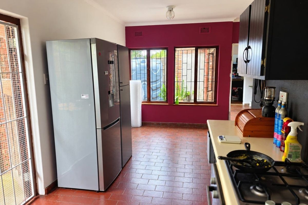 A functional kitchen featuring tiled flooring, built-in cabinetry, and a gas hob, with direct access to the exterior through a glass door.