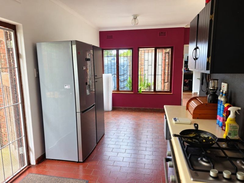 A functional kitchen featuring tiled flooring, built-in cabinetry, and a gas hob, with direct access to the exterior through a glass door.
