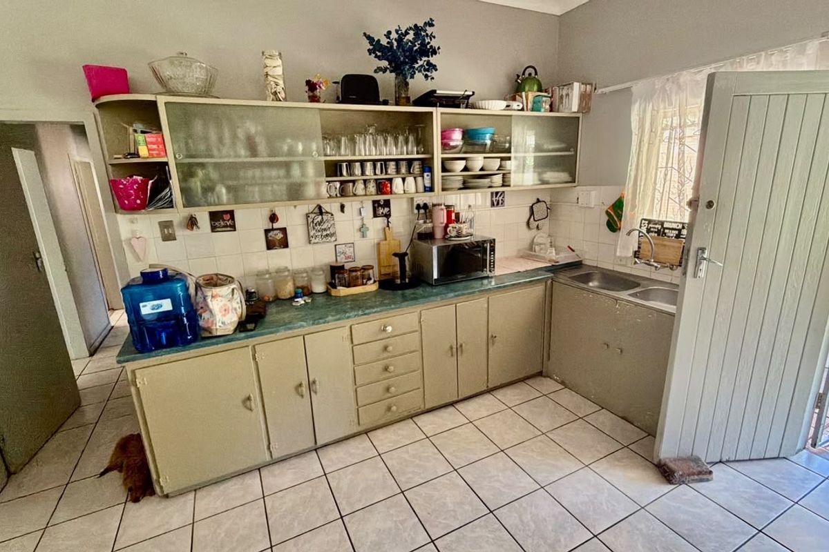 A functional kitchen featuring laminate countertops, ample built-in cabinetry, and a double basin sink, offering a practical layout with potential for modern updates.
