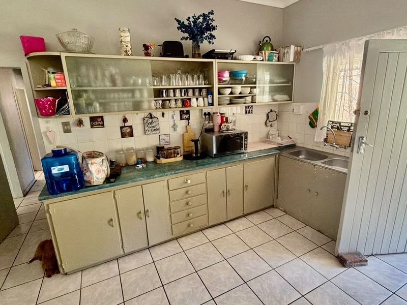 A functional kitchen featuring laminate countertops, ample built-in cabinetry, and a double basin sink, offering a practical layout with potential for modern updates.