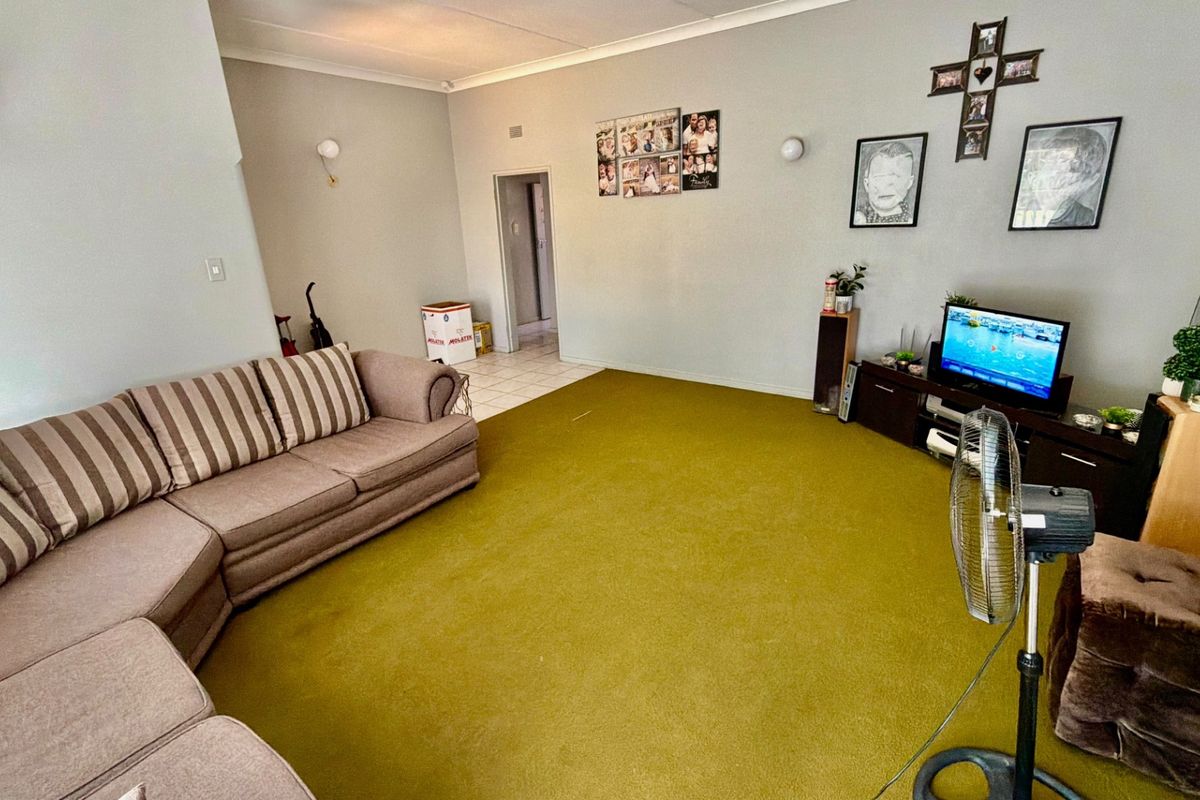 A living room featuring wall-to-wall carpeting and cove cornice detailing, offering a functional space with potential for modernization.