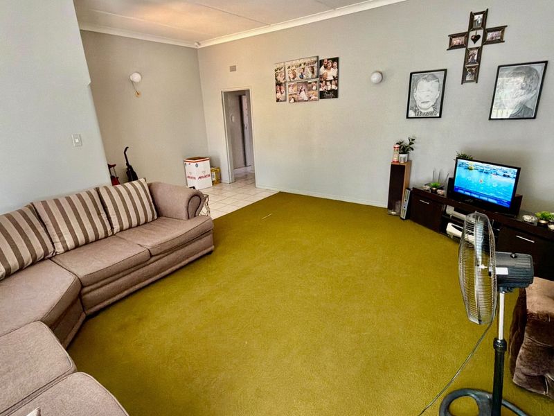 A living room featuring wall-to-wall carpeting and cove cornice detailing, offering a functional space with potential for modernization.