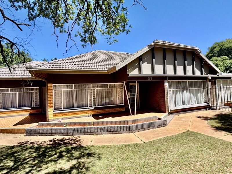 Front elevation of a single-story house featuring a tiled roof, brick facade, timber decking, and a paved walkway leading to the entrance.
