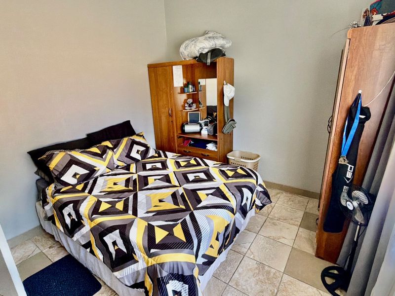 A functional bedroom featuring tiled flooring and neutral wall finishes, providing a practical space for rest.