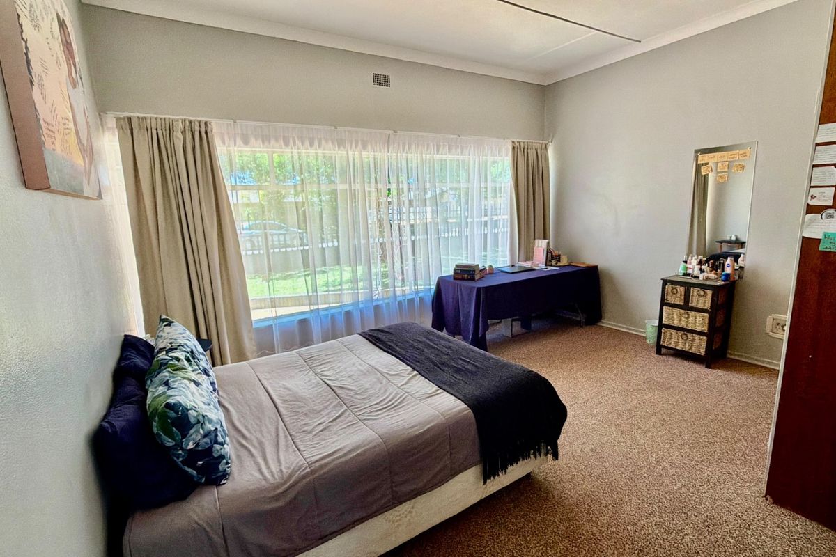 A spacious bedroom featuring large windows that provide ample natural light, neutral wall finishes, and carpeted flooring.