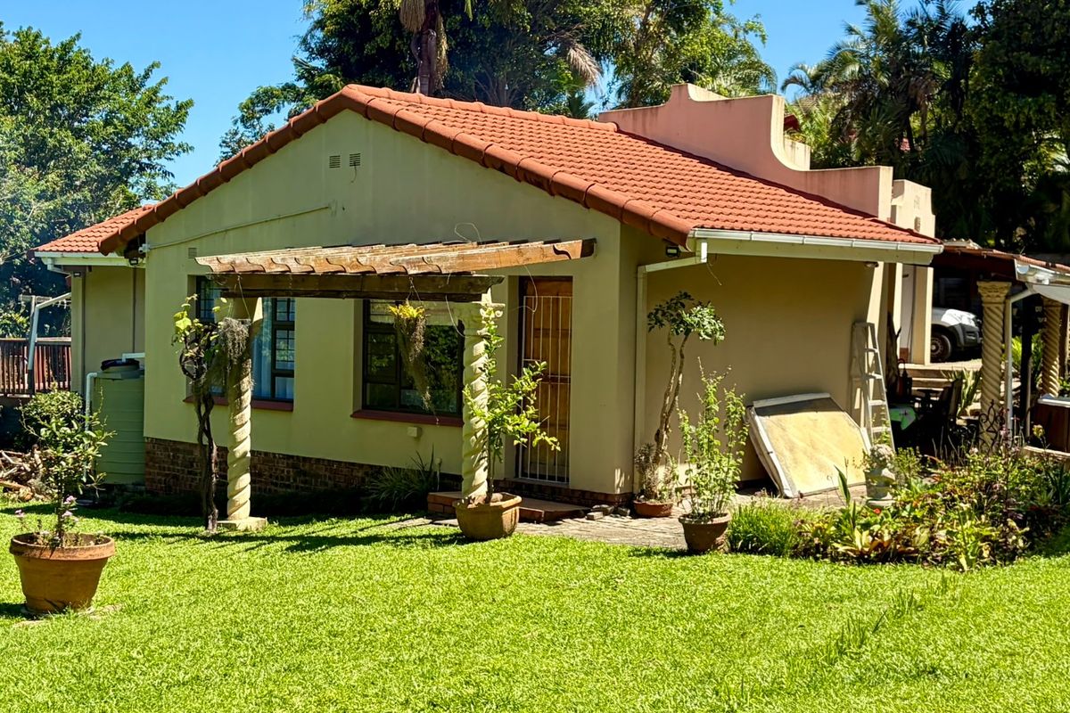 Rear view of the house featuring a terracotta tiled roof, a wooden pergola, and a well-maintained garden setting with established landscaping.