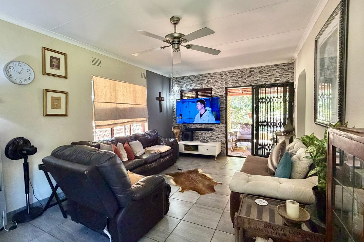 A comfortable living room featuring tiled flooring, a ceiling fan, and a stone veneer feature wall with direct access to an outdoor patio area.