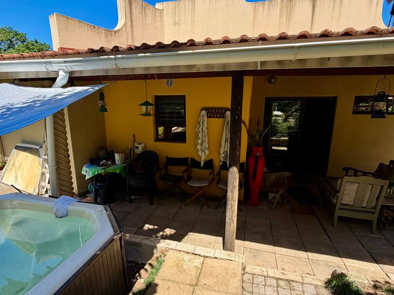 A covered outdoor patio area featuring tiled flooring, a built-in spa, and direct access to the home's interior living space.