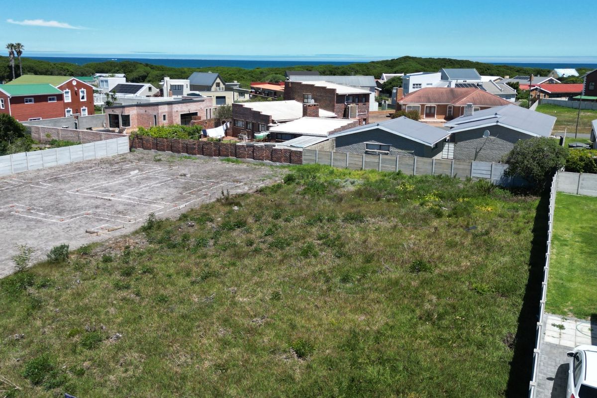 Aerial view of a vacant residential plot featuring established boundary walls and foundation layout markings, situated in a coastal neighborhood.