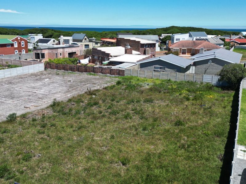 Aerial view of a vacant residential plot featuring established boundary walls and foundation layout markings, situated in a coastal neighborhood.