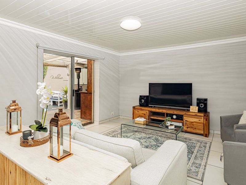 A bright living room featuring tiled flooring, a tongue and groove ceiling, and a sliding glass door providing access to the outdoor patio area.