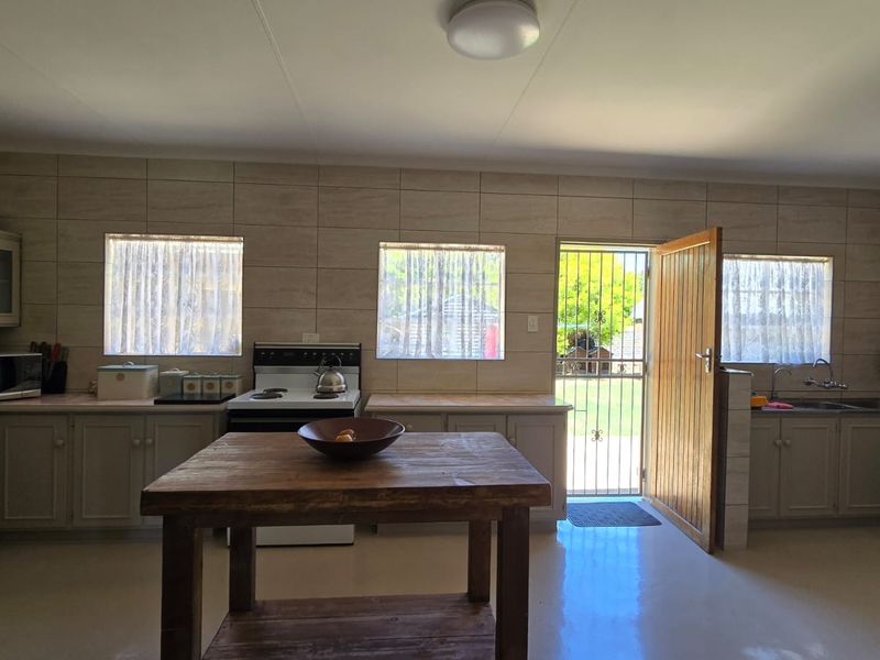 A functional kitchen featuring tiled walls, built-in cabinetry, a freestanding stove, and direct access to the exterior through a security gate.