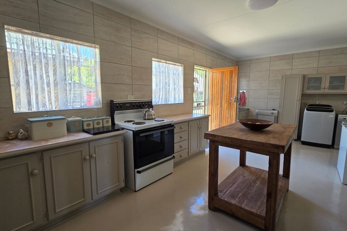A functional kitchen featuring tiled walls, built-in cabinetry, and a freestanding stove, with direct access to the exterior.