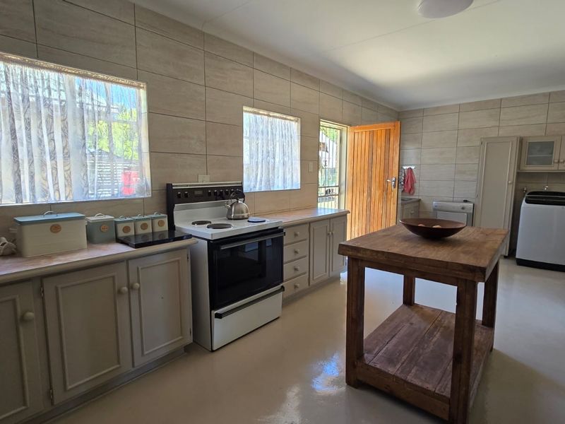 A functional kitchen featuring tiled walls, built-in cabinetry, and a freestanding stove, with direct access to the exterior.
