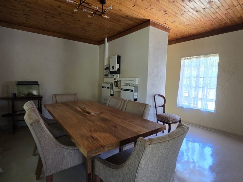 Dining room featuring a timber ceiling, tiled flooring, and a wall-mounted solar inverter and battery storage system.