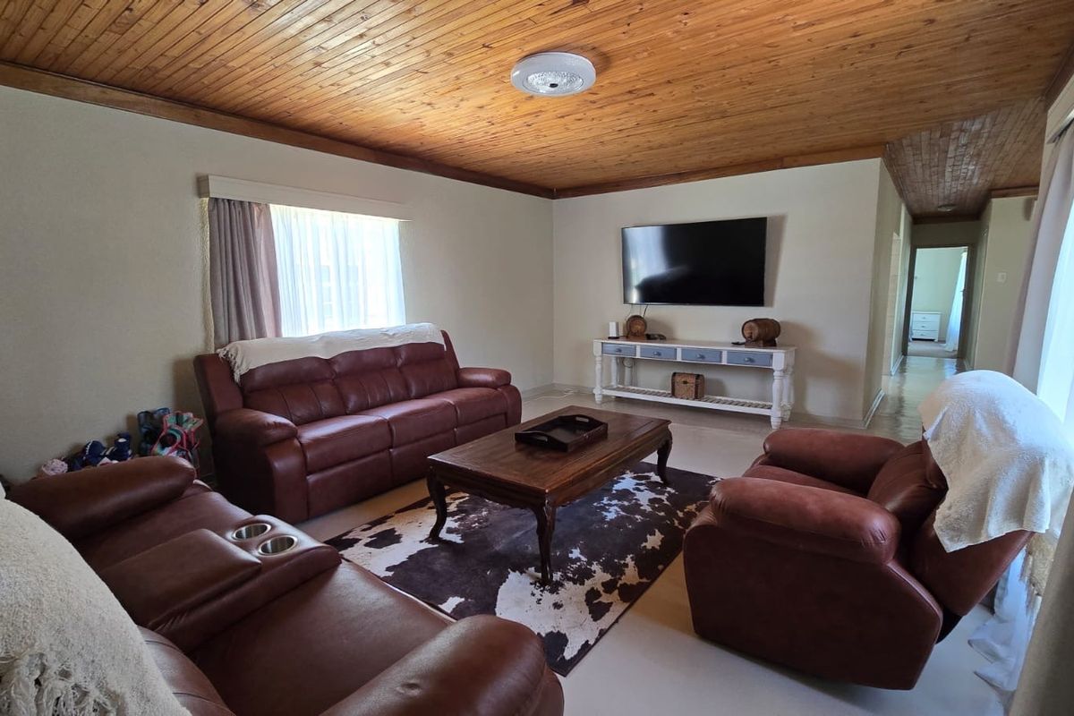 Spacious living room featuring a warm timber tongue and groove ceiling, neutral wall finishes, and tiled flooring, providing a comfortable and inviting atmosphere.