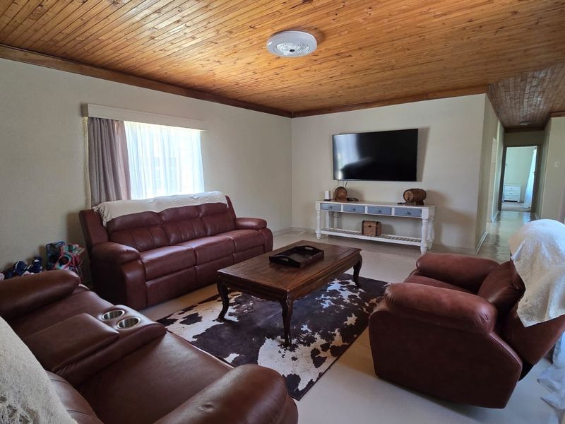 Spacious living room featuring a warm timber tongue and groove ceiling, neutral wall finishes, and tiled flooring, providing a comfortable and inviting atmosphere.