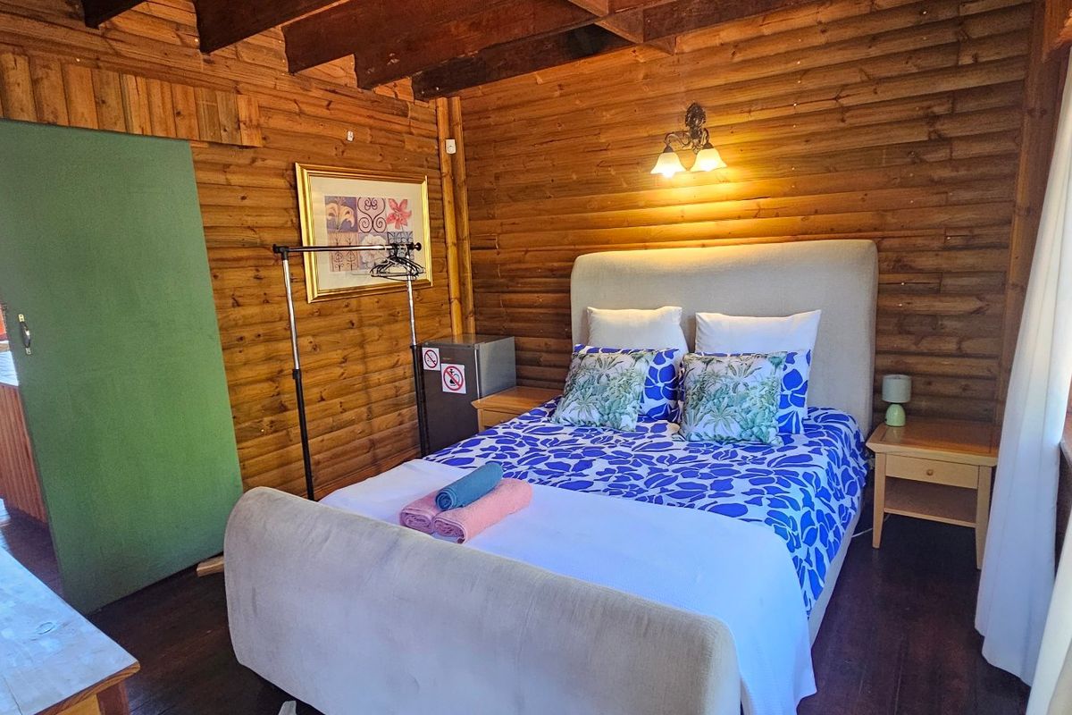 A cozy bedroom featuring rustic exposed timber log walls and exposed ceiling beams, creating a warm and traditional cabin-style atmosphere.