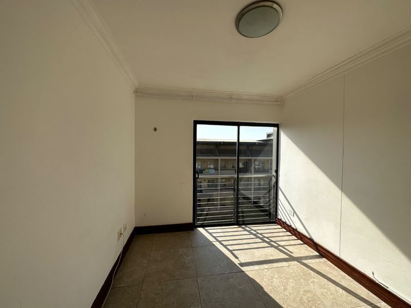 An empty bedroom featuring tiled flooring, coving, and a sliding glass door that provides natural light and access to the exterior.
