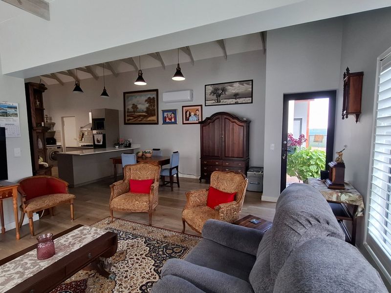 Spacious open-plan living and kitchen area featuring exposed timber ceiling beams, modern air conditioning, and large shutter blinds for natural light control.
