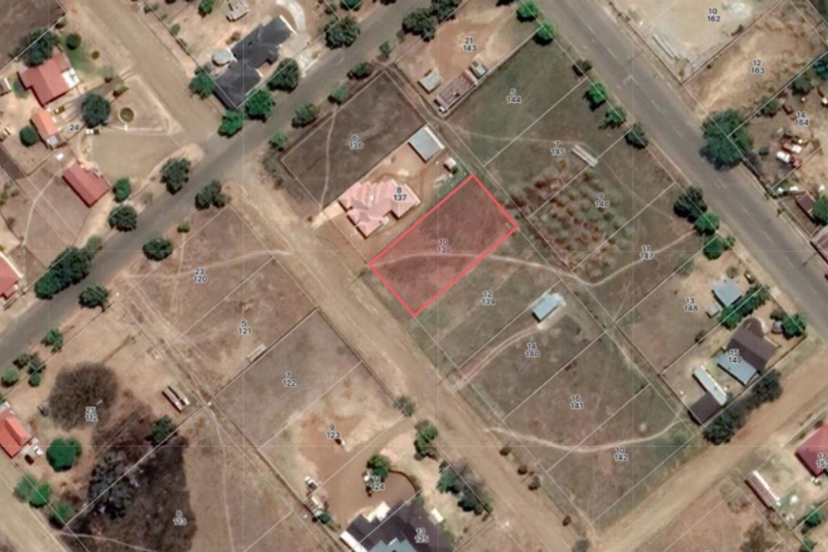 Aerial view of a vacant residential plot highlighted in red, situated within an established neighborhood.