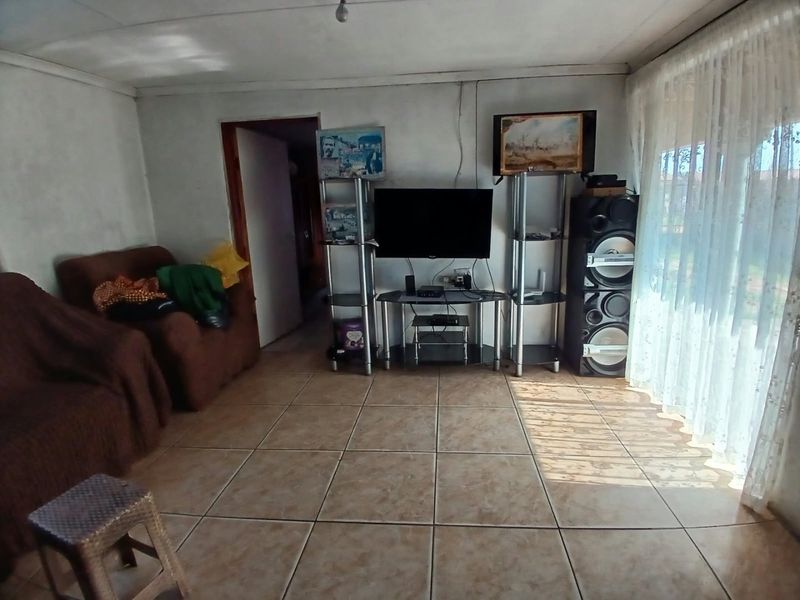 A living room featuring tiled flooring and a large sliding glass door, providing natural light and access to the exterior.