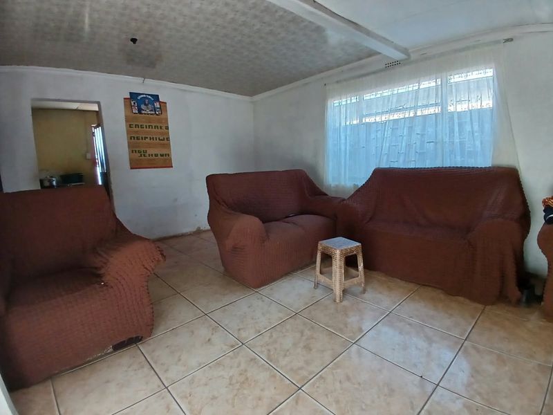 A living room featuring tiled flooring and a large window, providing a functional space with potential for cosmetic updates.