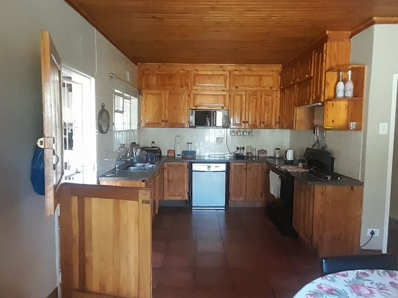 A functional kitchen featuring extensive wooden cabinetry, tiled flooring, a timber ceiling, and a built-in oven with a tiled backsplash.