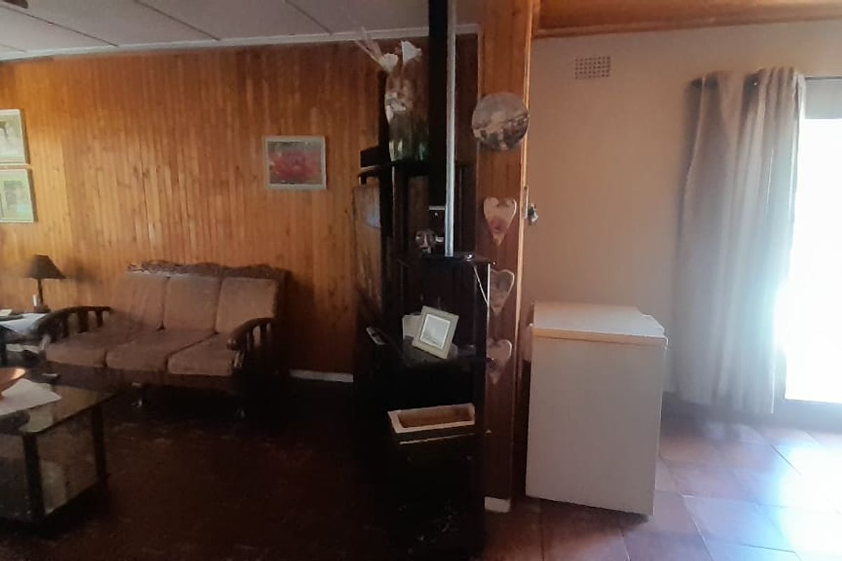 Living area featuring wood paneling, tiled flooring, and a sliding glass door providing natural light.