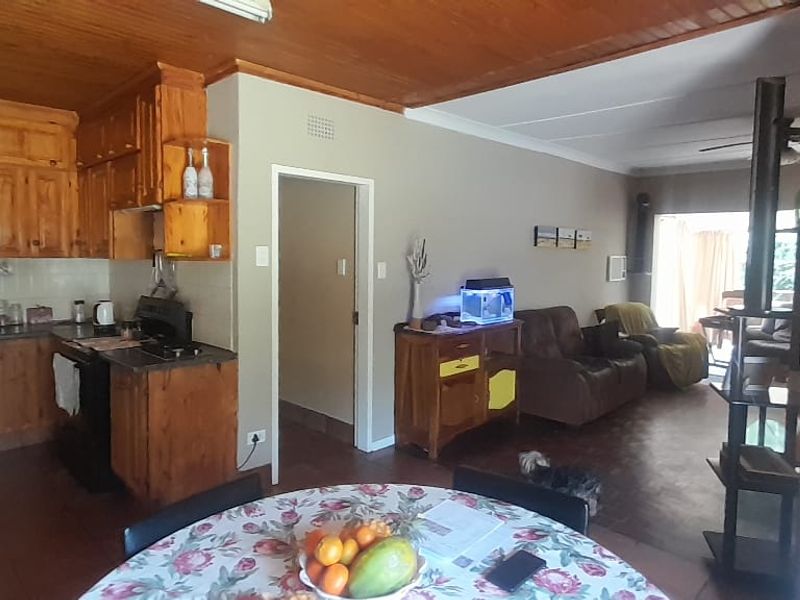 Open plan kitchen and living area featuring wooden cabinetry, tiled flooring, and a wooden ceiling, offering a functional layout with potential for modern updates.