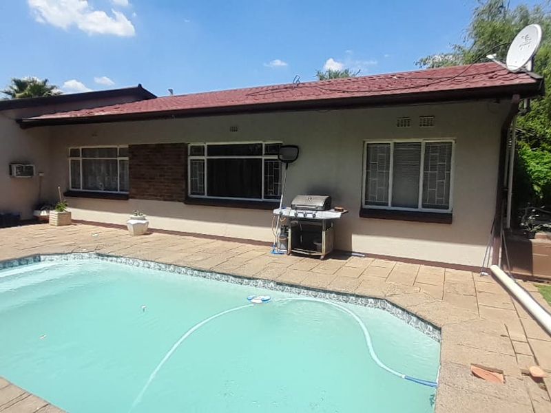 Rear exterior view featuring a swimming pool, paved patio area, and direct access to the home via sliding glass doors.