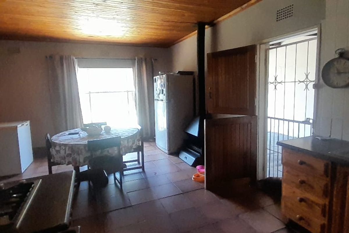 A dated kitchen featuring wood-paneled ceilings, tiled floors, and a built-in wood-burning fireplace, offering potential for a modern renovation.