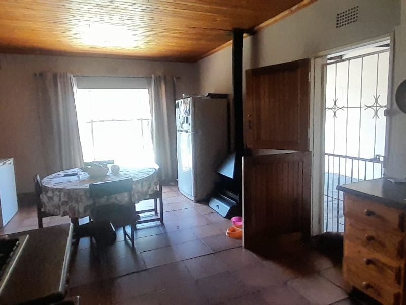 A dated kitchen featuring wood-paneled ceilings, tiled floors, and a built-in wood-burning fireplace, offering potential for a modern renovation.