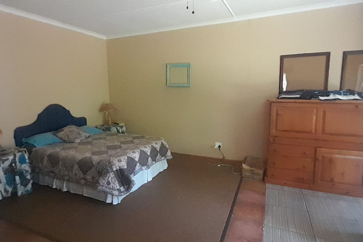 Spacious bedroom featuring a split-level floor design with a combination of carpet and tile flooring, offering potential for modernization.