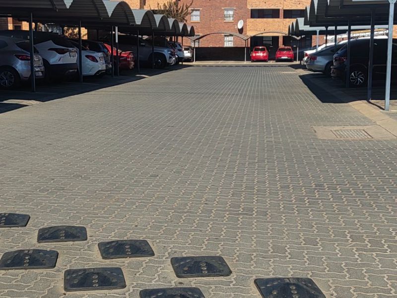 Exterior view of the apartment complex parking area featuring paved driveway and covered parking bays.