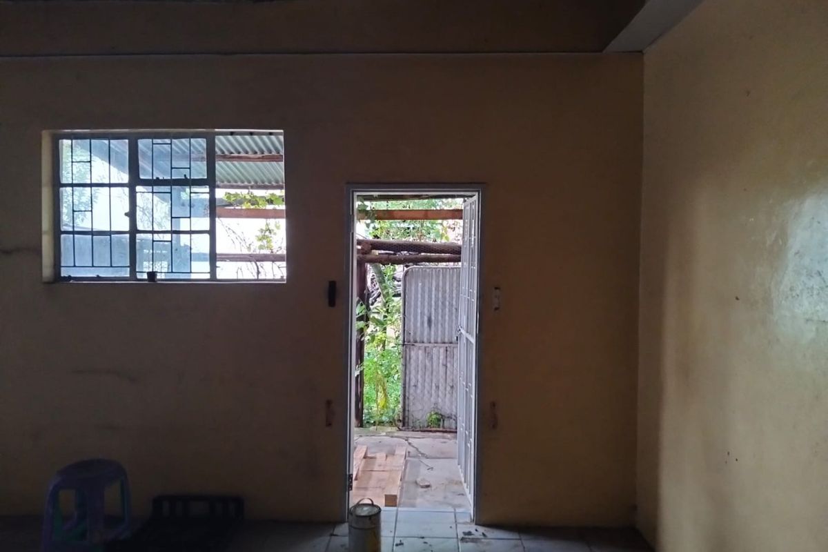 An empty, unfinished interior space featuring tiled flooring, a steel-framed window, and a security gate leading to an outdoor area.