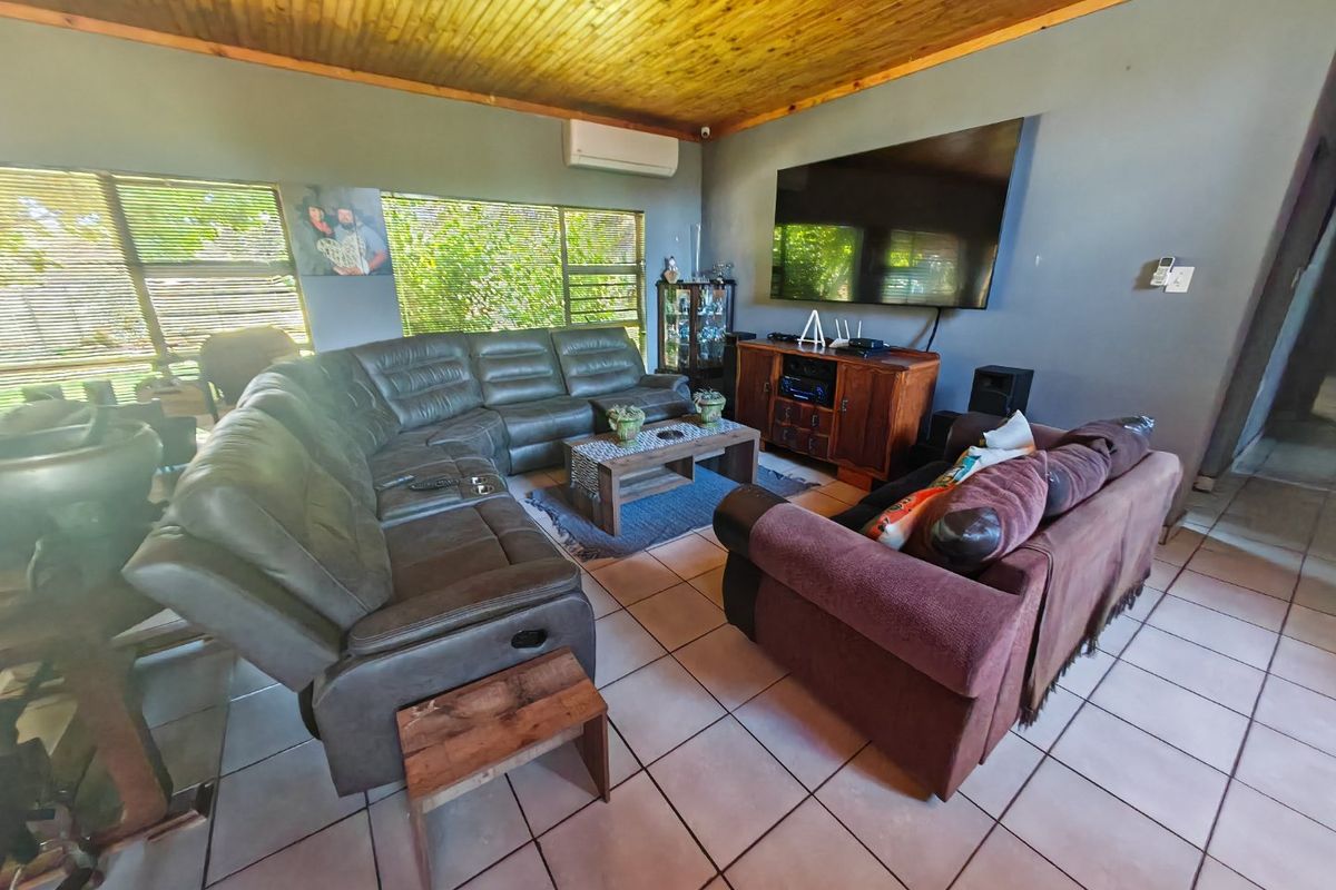 A spacious living room featuring a warm timber-clad ceiling, tiled flooring, and a wall-mounted air conditioning unit.
