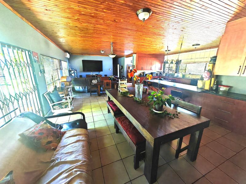 Spacious open-plan living and kitchen area featuring a distinctive timber ceiling, tiled flooring, and a functional kitchen island layout.