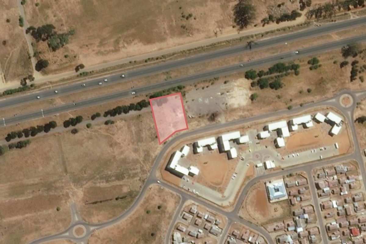 Aerial view of a vacant residential land parcel situated near a main road and existing residential development.