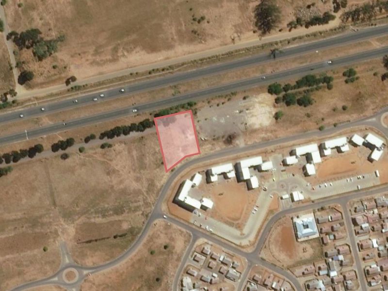 Aerial view of a vacant residential land parcel situated near a main road and existing residential development.